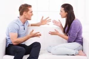 Confrontational couple. Furious young man and woman shouting at each other and gesturing while sitting on the couch