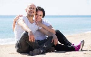 mature happy spanish couple smiling holding each other on the beach